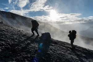 Climbers are backlit by the sunrise.