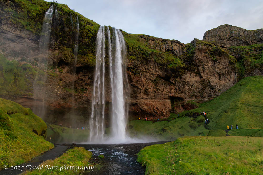 People hike around Seljalandsfoss just before sunset.