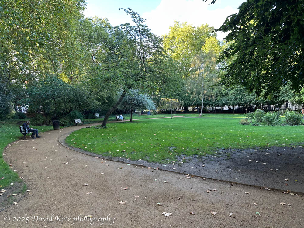 A small, quiet park with a person sitting on a bench.