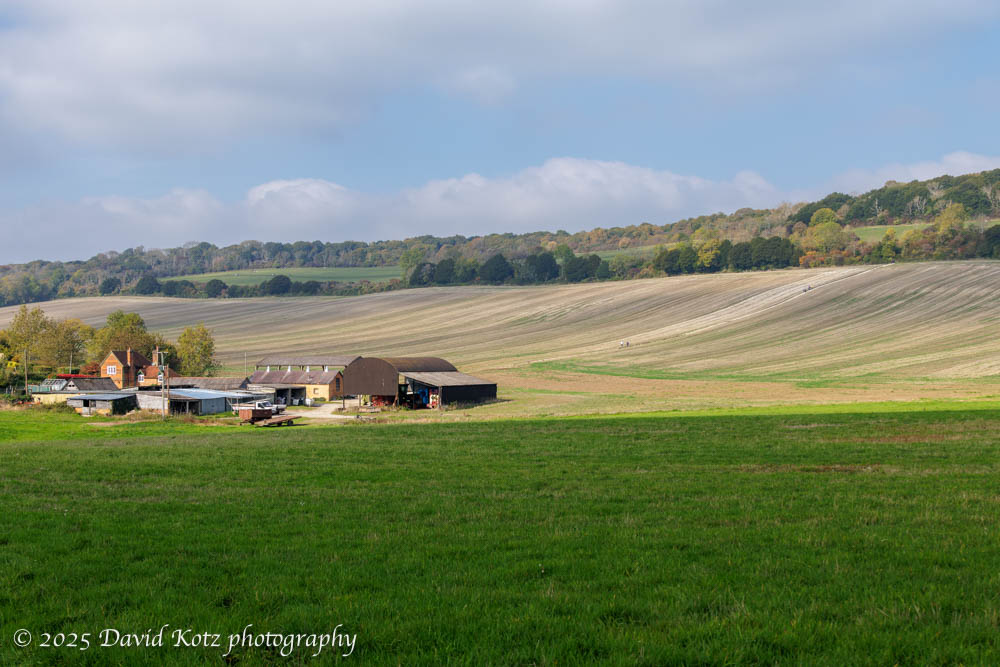 A farm with vast fields, with distant view of farmhouse and barn.
