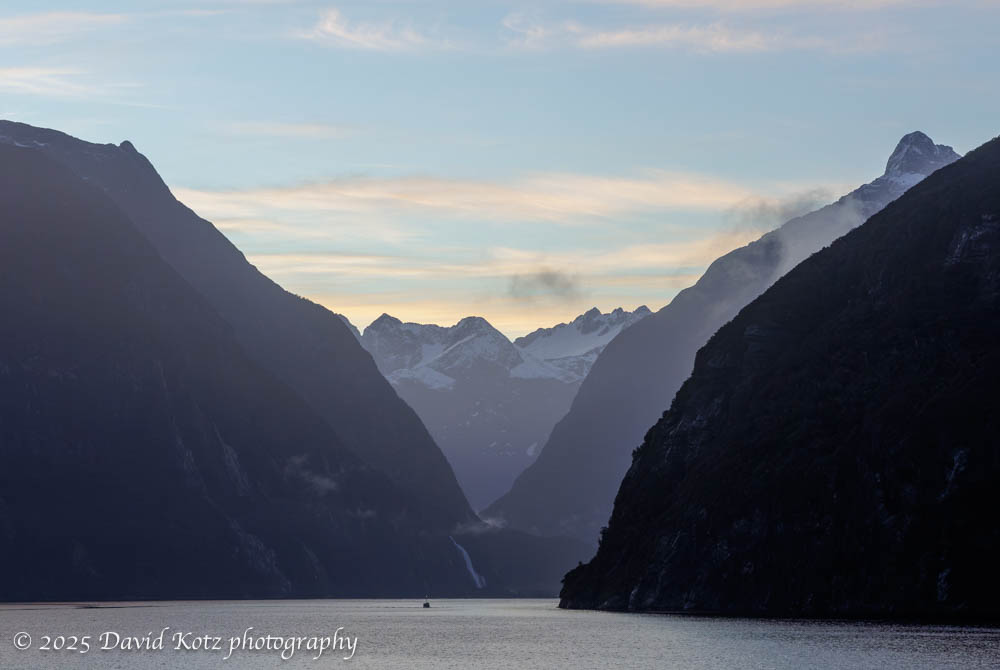Milford Sound's steep walls and distant mountains, in pre-dawn light.