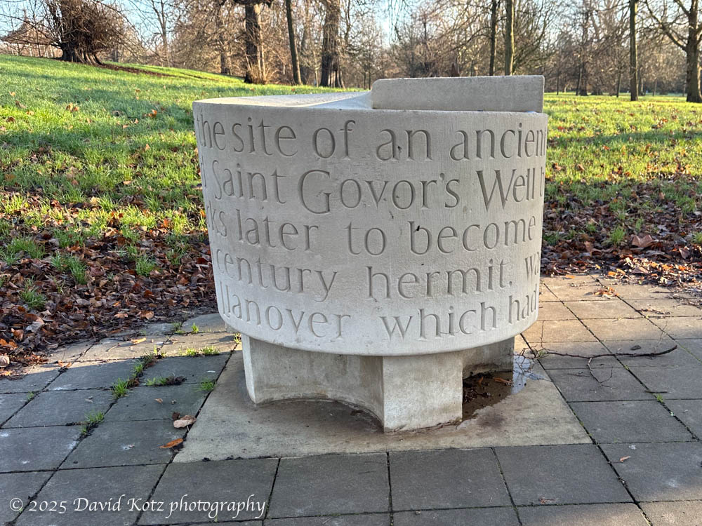 photo of a round drinking fountain, with large letters inscribed on the sides